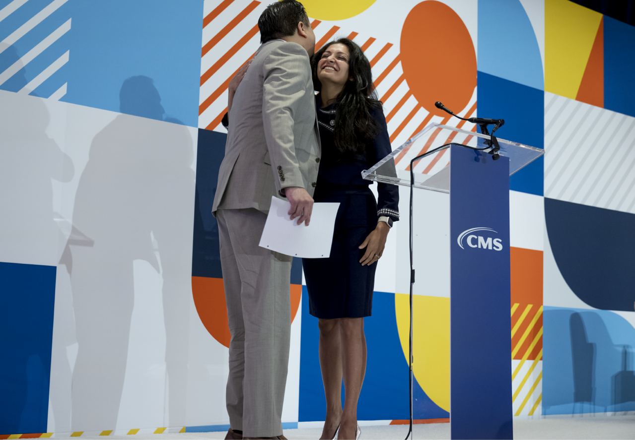 Man and woman greet each other with a hug at the podium