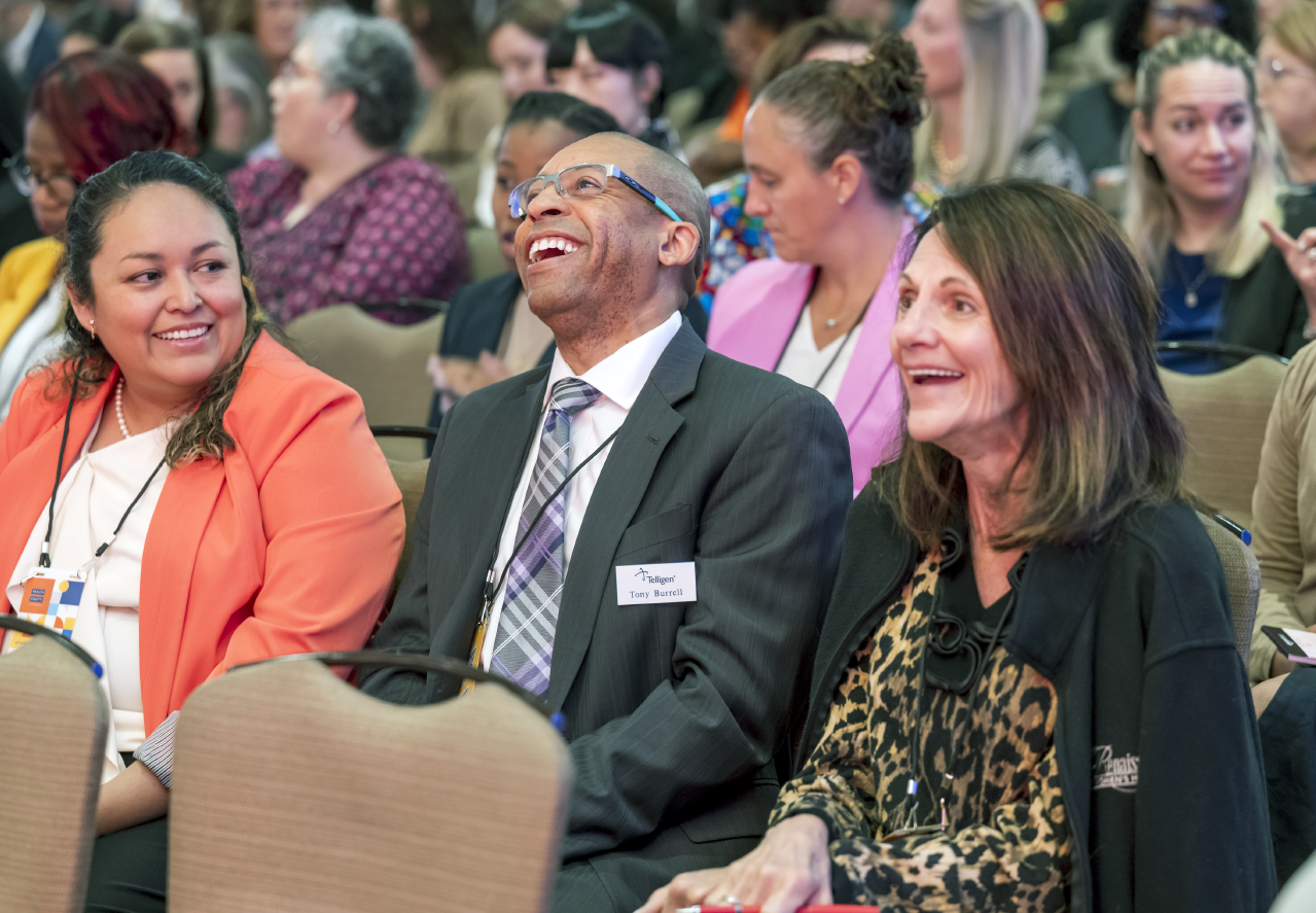 Photo of a group of people sitting at a conference laughing