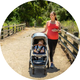 Pregnant woman walking on a nature path with her baby in a stroller