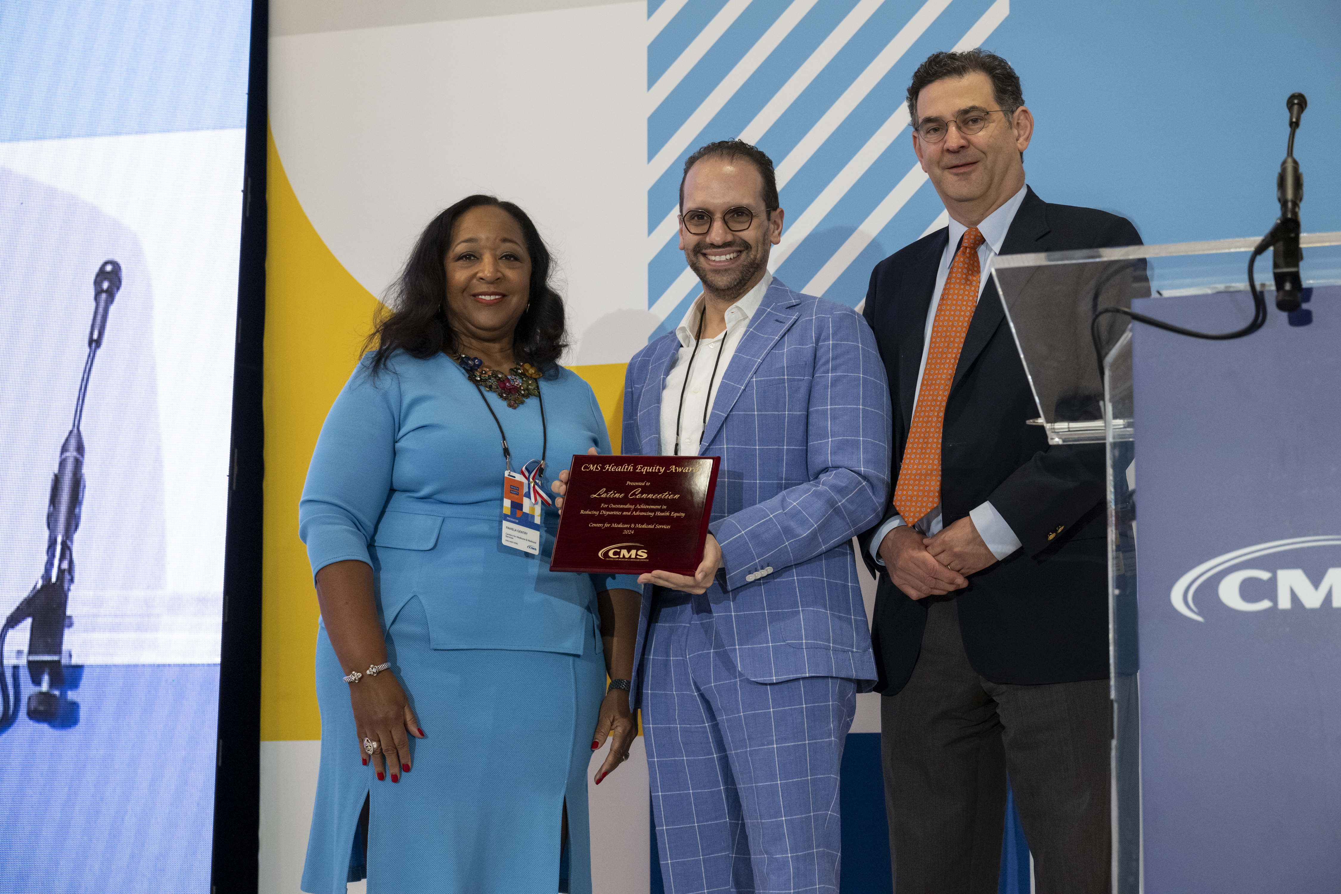 A gentleman holding an award between a woman and another man