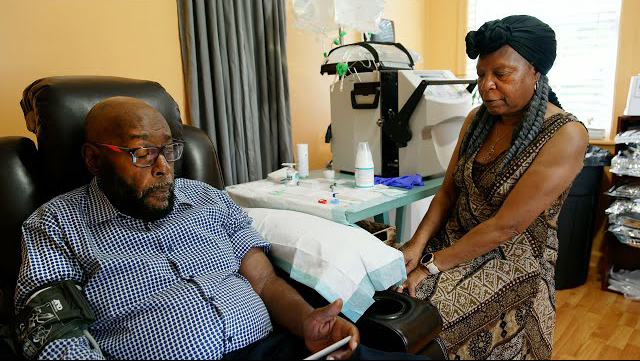 Connor Samuel and his wife Jacqueline are shown in their living room, with Jacqueline administering Connor's home dialysis